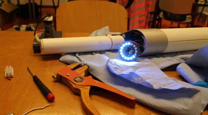 The battery ring lit inside the tube, on a table of wire strippers and offcuts.