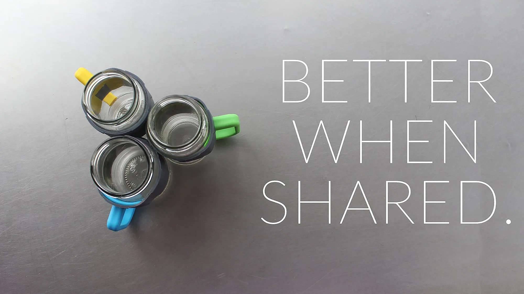 Three jars wearing yellow, green and blue handles, seen from above, handles pointing outwards, with the words Better when shared