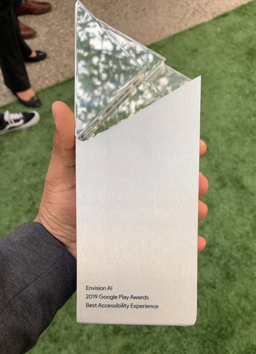 The 2019 Google Play Award in my hand, a brushed metal wedge engraved “Envision AI, 2019 Google Play Awards, Best Accessibility Experience”.