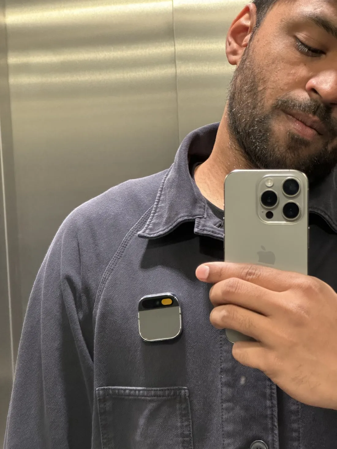 The Humane AI Pin clipped to my jacket, photographed in a lift mirror.