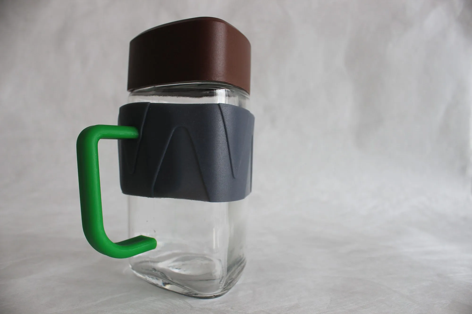 A square jar with a wooden lid wearing a green Jarry handle