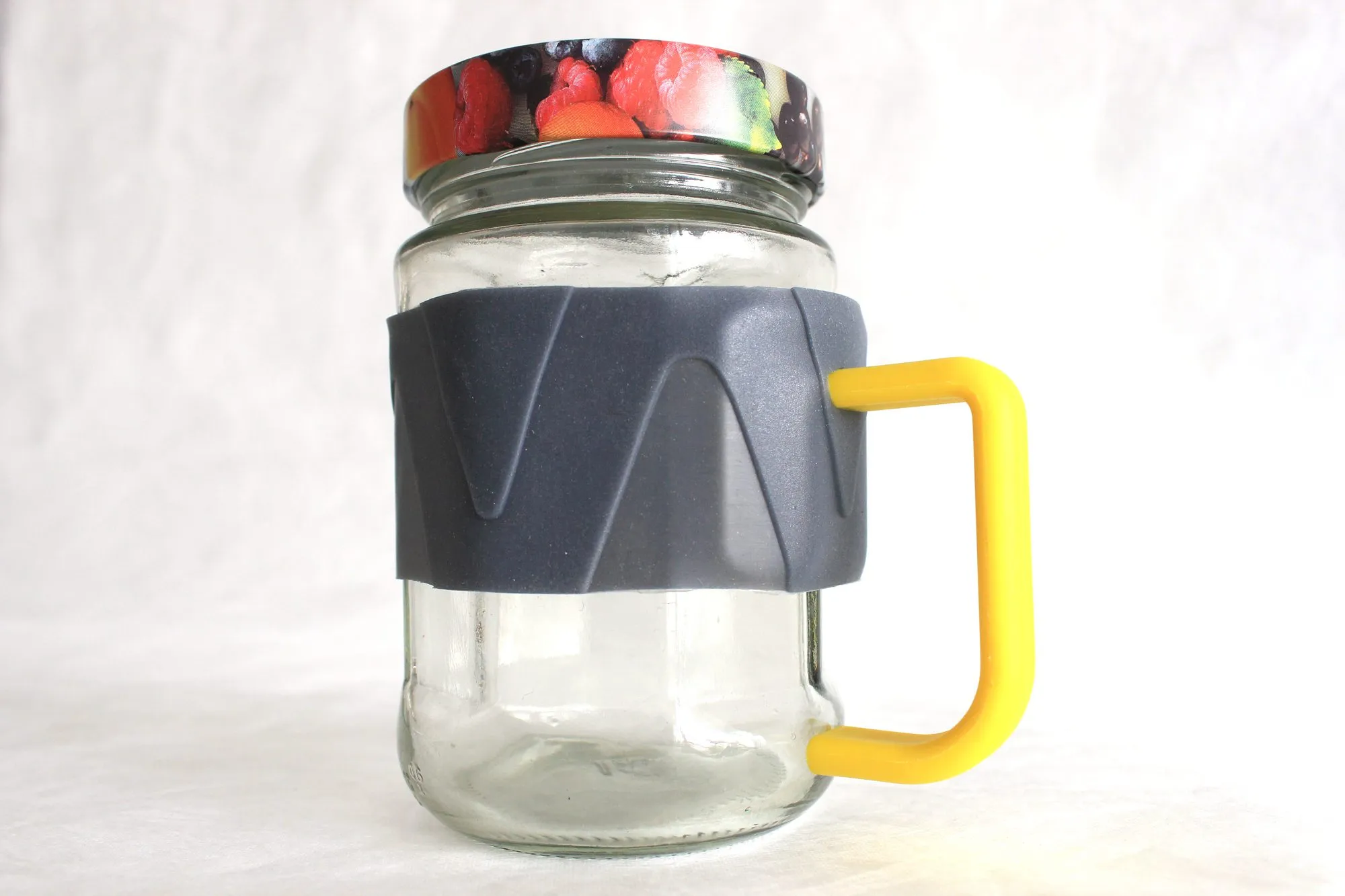 Jarry on a jam jar with a fruit-print lid: a grey band with a raised chevron pattern and a yellow D-shaped handle