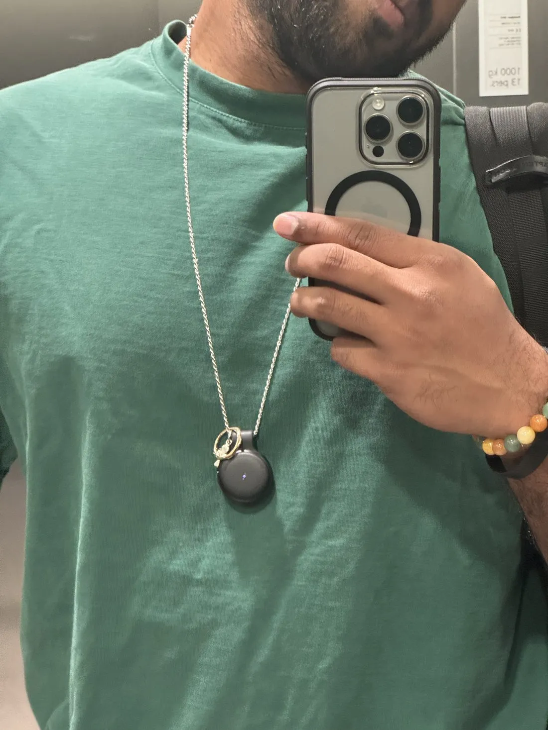 The Limitless Pendant hanging on a chain over a green t-shirt, same mirror.