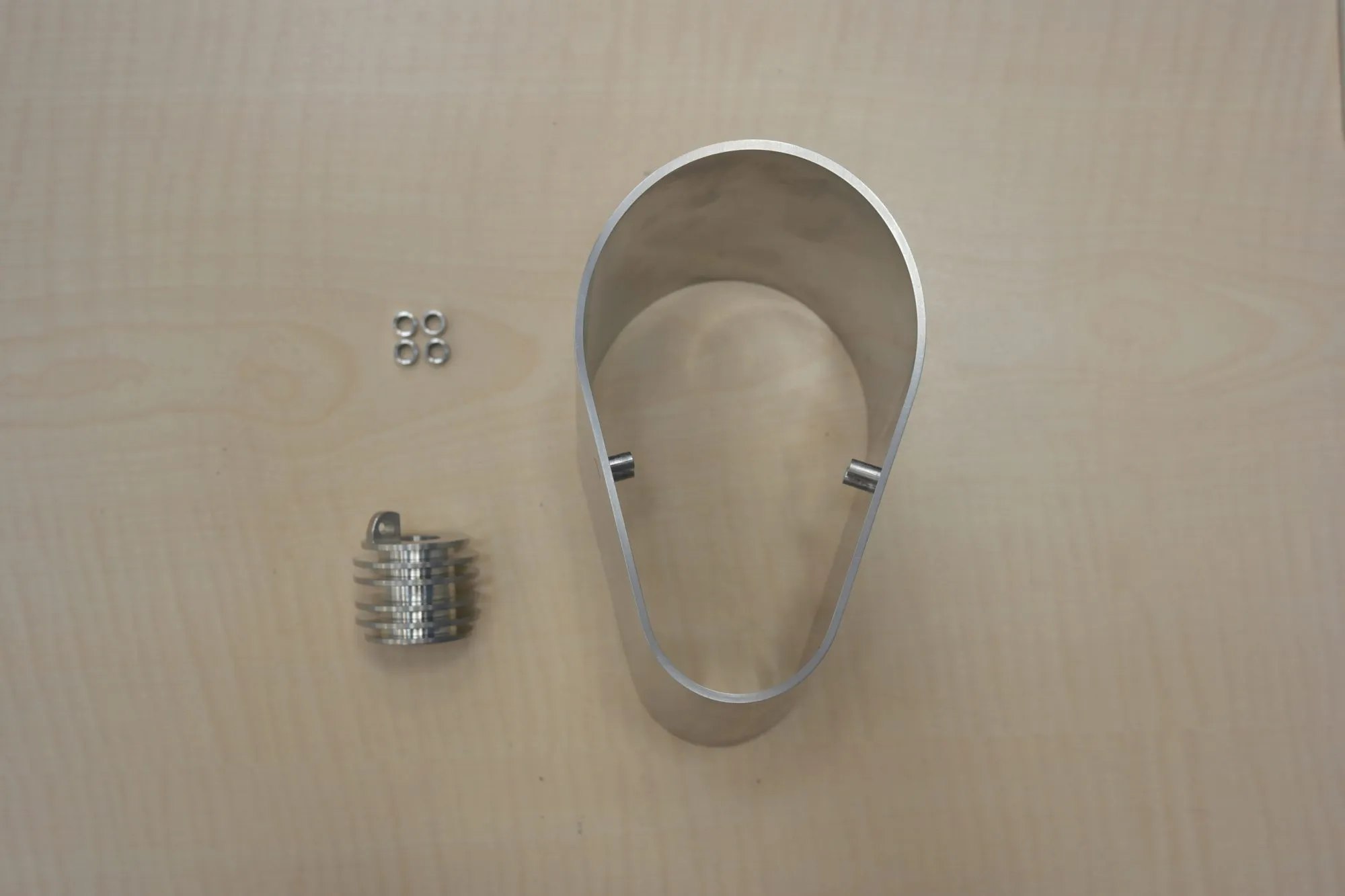 The machined bracket with its pins, next to the other turned metal parts.