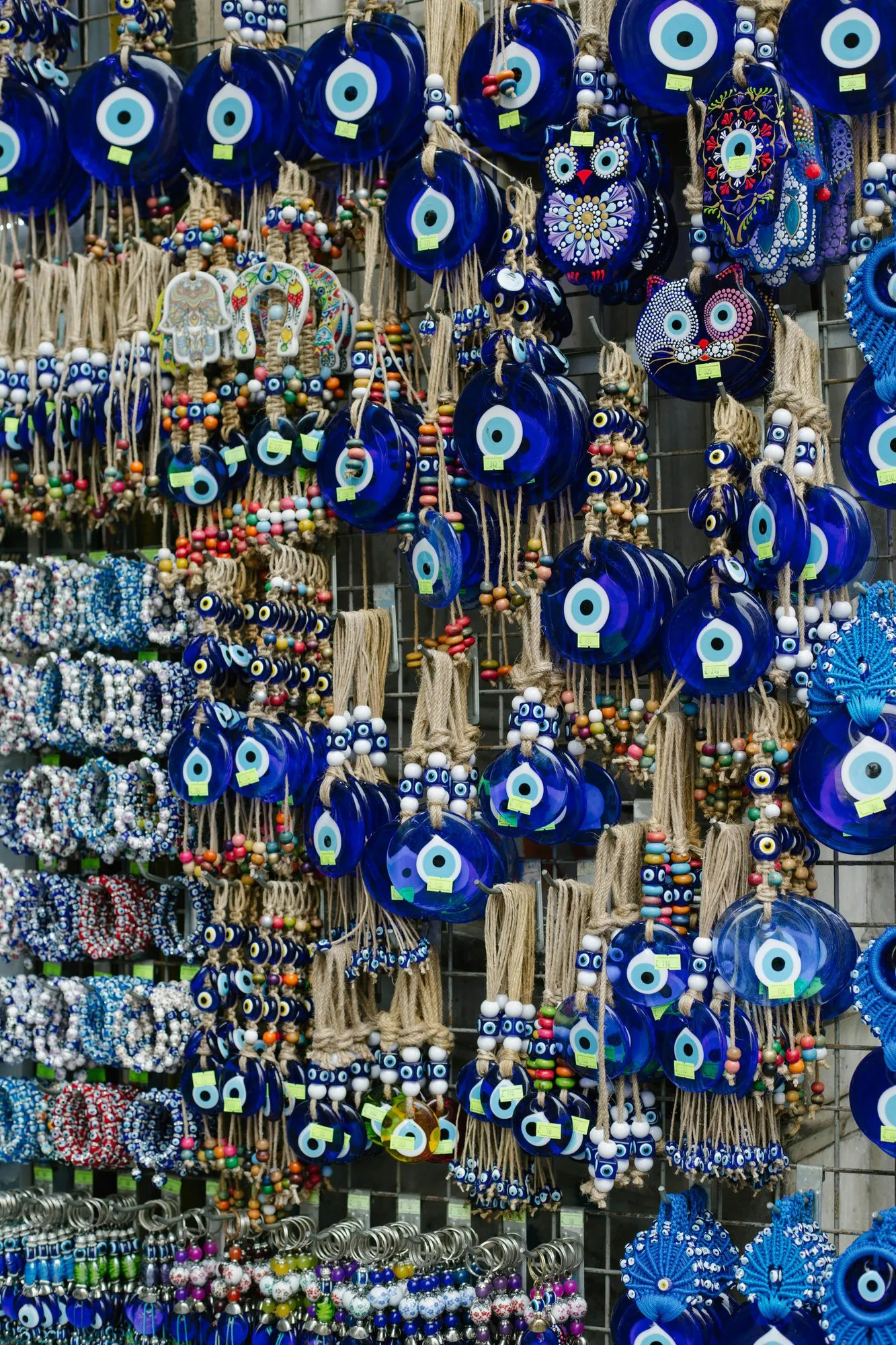 A bazaar stall covered wall to wall in blue glass nazar boncuğu charms, hanging from jute cords with colorful beads