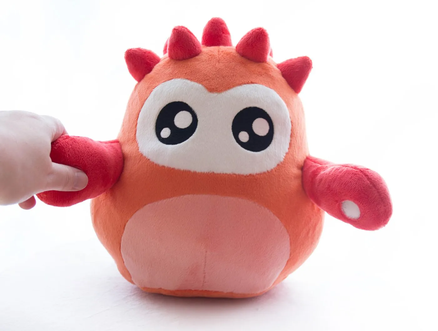The finished Onky plush, a hand squeezing one of its paws