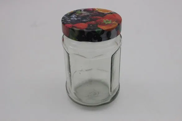 An empty hexagonal jam jar with a fruit-print lid