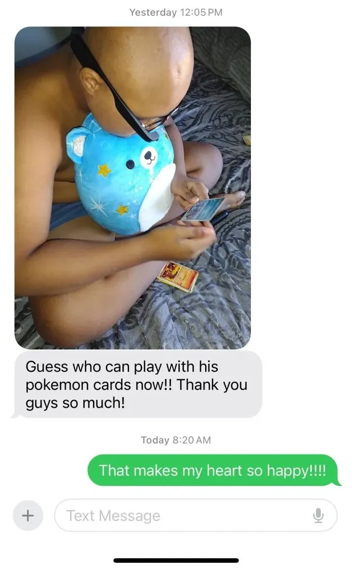 The message thread: a photo of a small boy sitting cross-legged on his bed in Envision Glasses, hugging a blue teddy bear and looking down at the Pokémon card in his hand. Underneath it his family wrote “Guess who can play with his pokemon cards now!! Thank you guys so much!”, and our reply the next morning, “That makes my heart so happy!!!!”