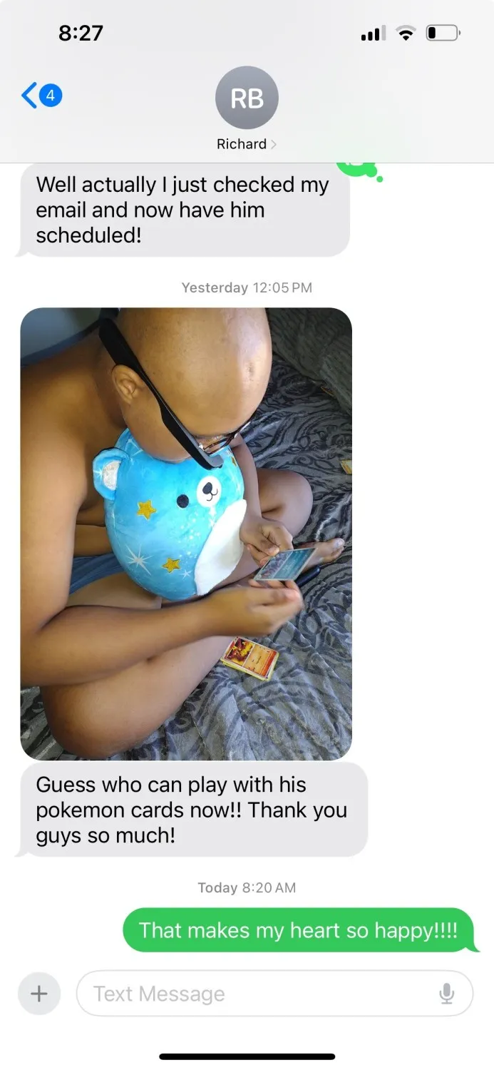  A text message thread showing a conversation with a person named Richard. Below the message is a photo of a bald child sitting cross-legged on a bed while holding a blue stuffed bear with yellow stars. The child is wearing assistive glasses and looking at Pokémon cards. The caption reads, “Guess who can play with his Pokémon cards now!! Thank you guys so much!”