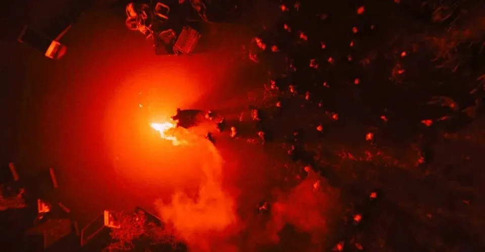 Alt: Batman holding a red flare leading a group of people through the flood